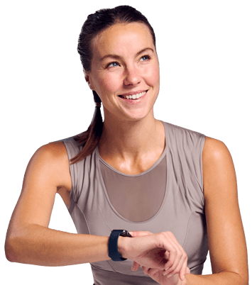 Caucasian woman looking up with a smile, braided hair with a nude color sports attire, holding her smartwatch on her wrist